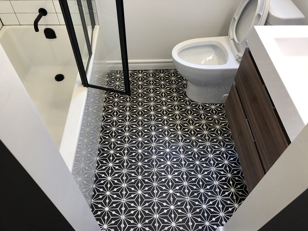 Timeless design meets modern luxury: Black knox cement tiles elevate a bathroom with a white walk-in shower and black faucets