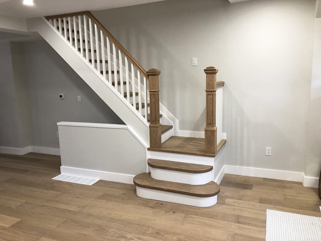 Clean and modern staircase design with warm wood treads, a white painted railing, and a comfortable feel.